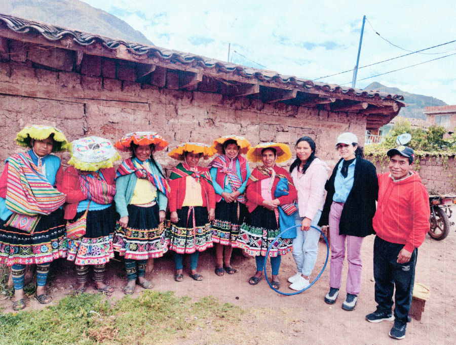 sieben Frauen aus Peru, sechs davon in ihren Trachten. Eine siebte Frau als Verantwortliche für Projekte in Südamerika sowie ein weiterer Peruaner stehen vor einem Haus.